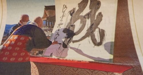 Two elderly Japanese men paint the Japanese character ikusa.